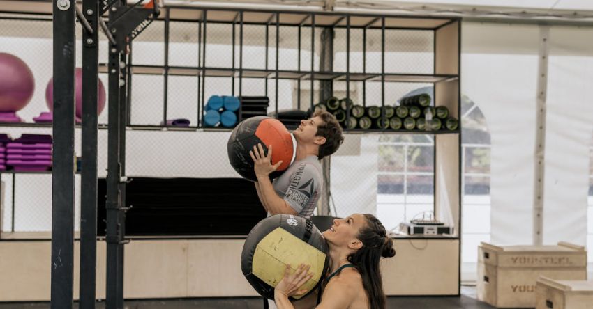 Medicine Balls - Man and Woman Lifting Medicine Balls at the Gym