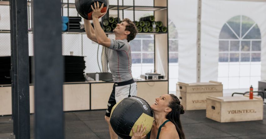 Medicine Balls - Man and Woman Working Out at the Gym