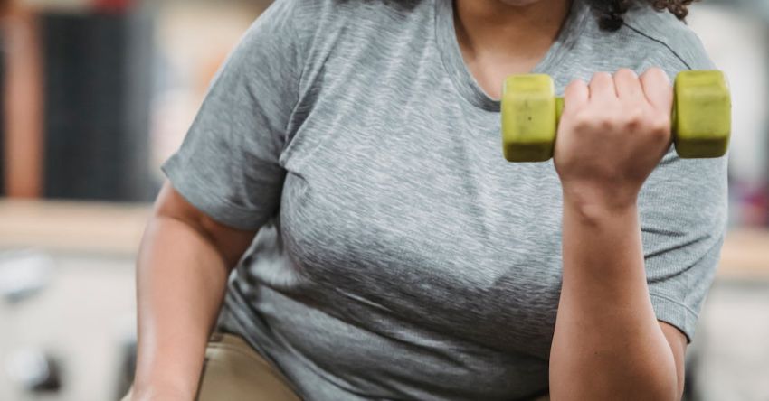 Weight Bench Brands - Overweight black woman lifting dumbbell in gym