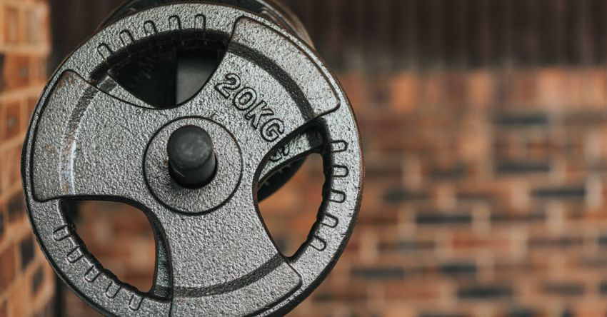 Dumbbell Form - Modern black dumbbell with circle shaped plates indicating weight number on solid surface in daylight