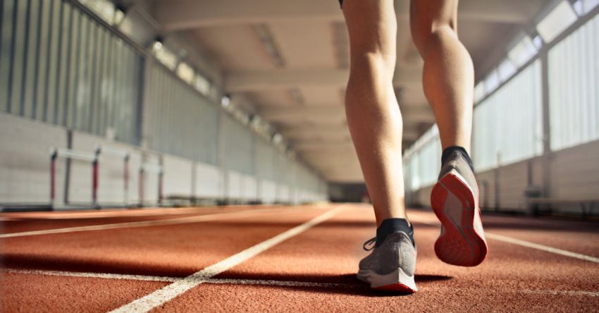 Low-Impact Workouts - From below back view of crop strong runner walking along running track in athletics arena while doing warm up exercises during workout