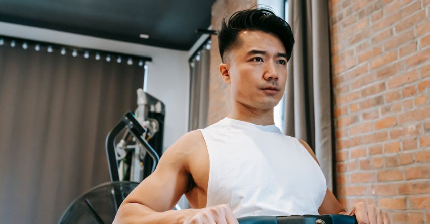 Rowing Machines - Young Asian man using gym equipment for keeping fit