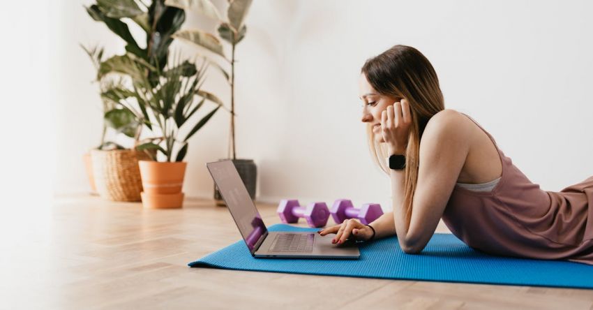 Fitness Tracker Brands - Young sportive woman using laptop on floor